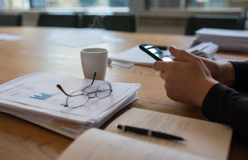 Smartphone och forskningsdokument på konferensbord under myndighetsutredning